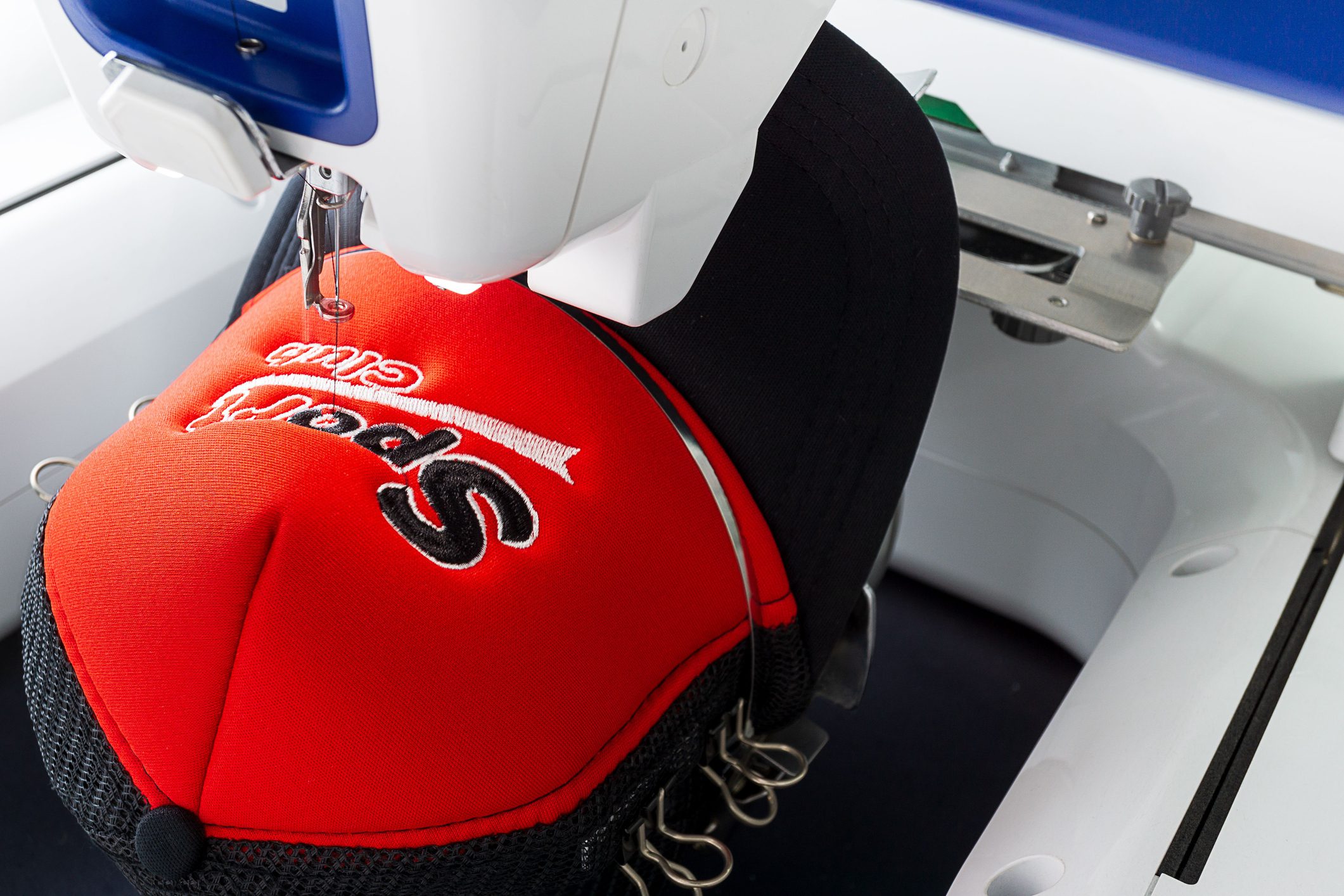 Working embroidery machine close up picture Embroidery machine stitching on red cap.