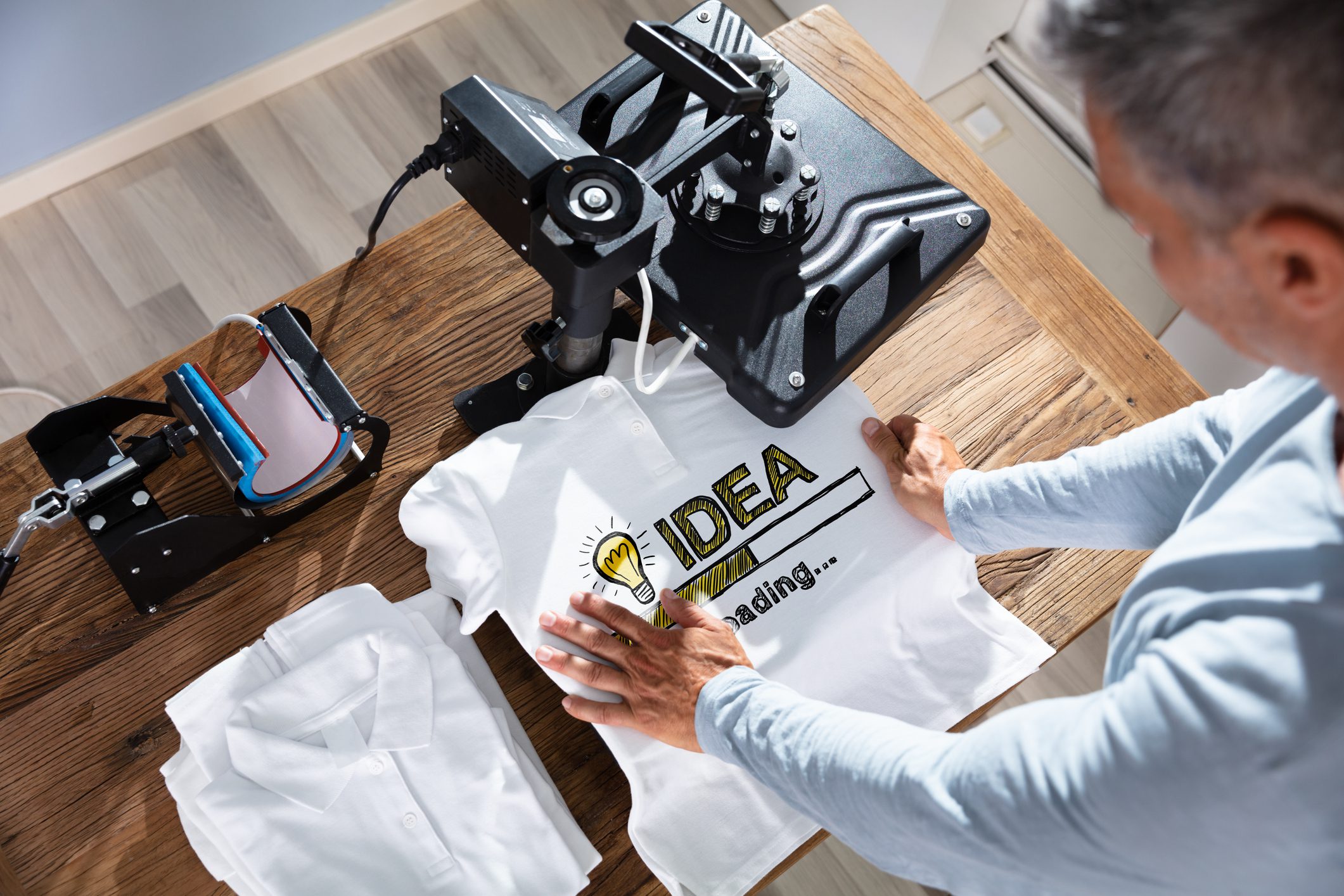 Man printing design on white t-shirt.
