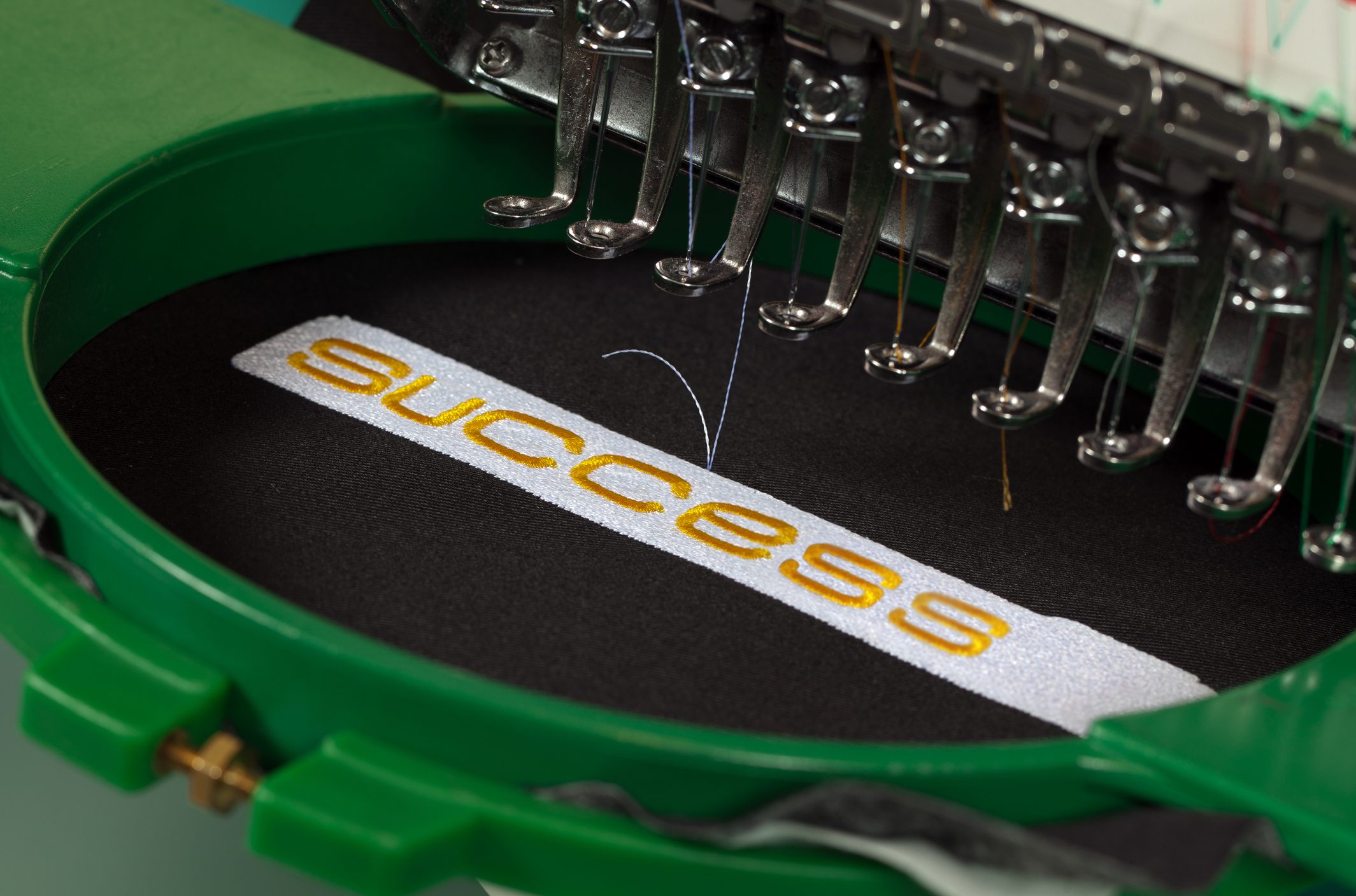 Embroidery machine stitching "success" text.